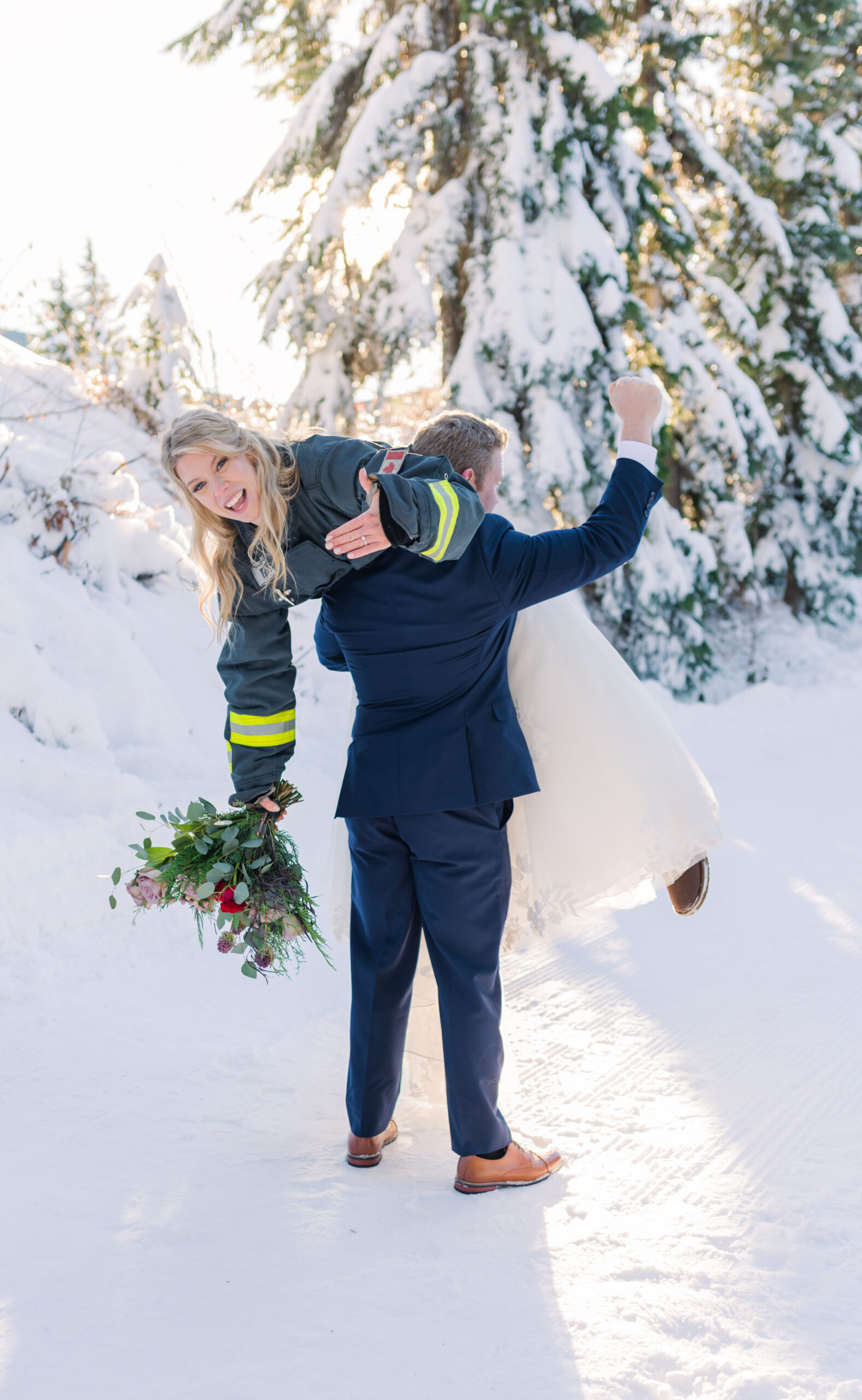 Groom-lifts-bride-over-his-right-shoulder-wearing-his-firefighter-jacket-on-wedding-day