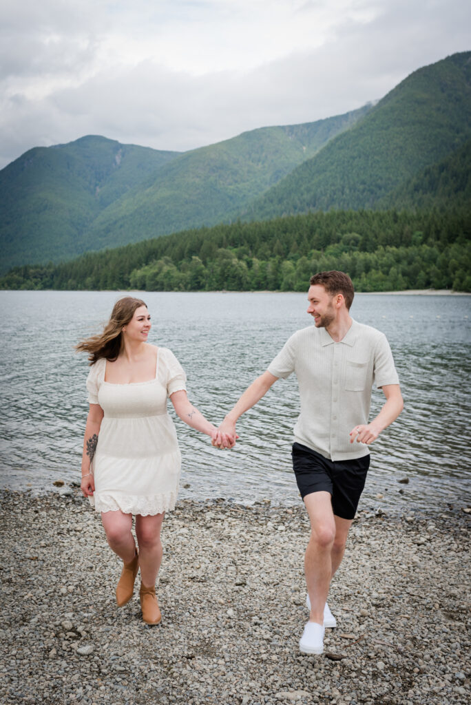 Girl and guy running at the beach holding hands and looking at each other in love.