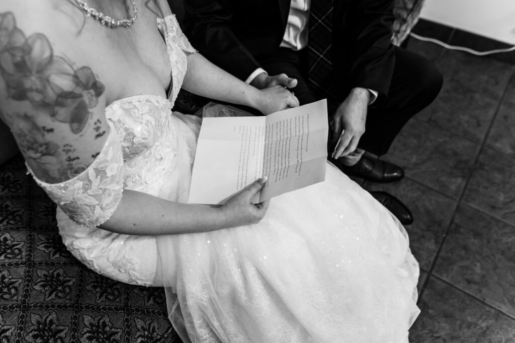 Personal vows on a piece of paper and bride and groom holding hands.