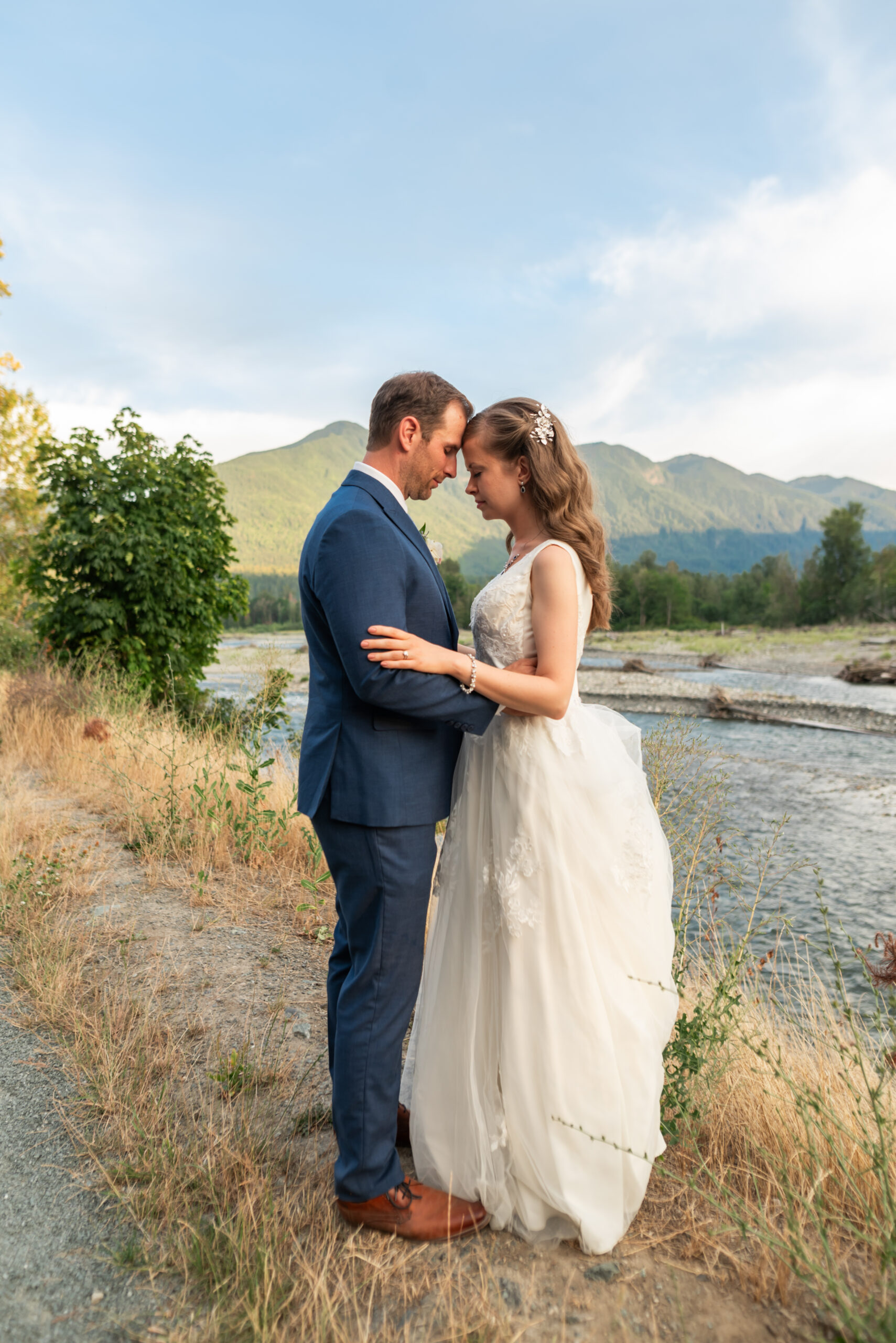 Bride-and-groom-touch-foreheads-and-arms. Fraser-River-in-the-back-round.