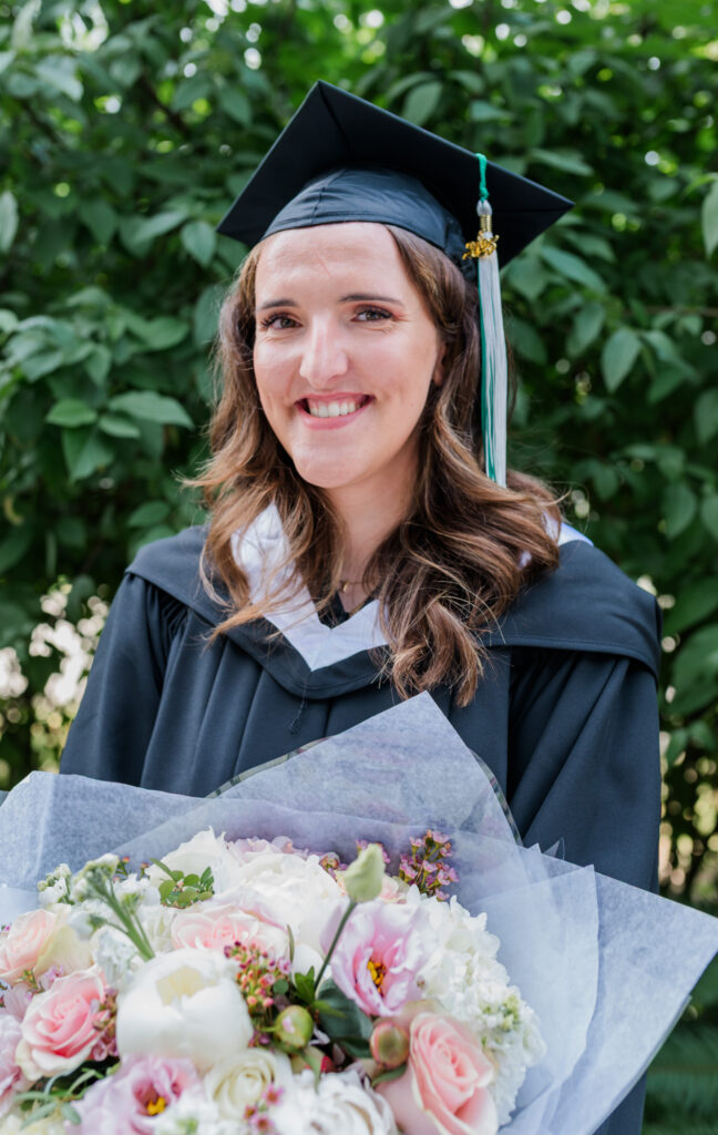 Jessica in her grad gown and cap holder her big bouquet of flowers.
