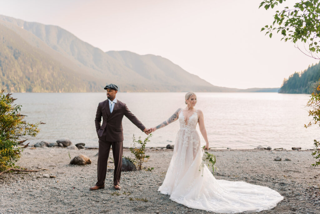 Bride and groom holding hands and looking different directions. North beach in the back round and mountains.