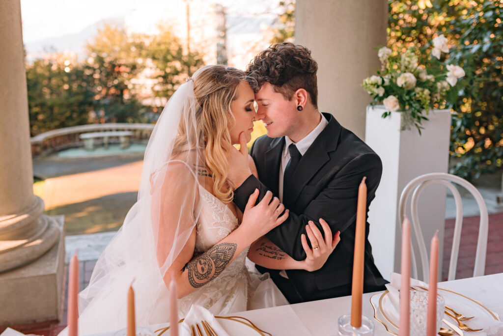 Bride and groom touching each other at the reception table before guests arrive. 
